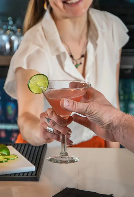 A bartender passes a martini across the bar.